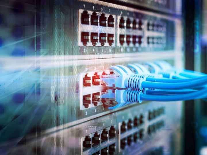 A close-up view of a network server with several Ethernet cables plugged into ports. The blue cables and various LED lights indicate connectivity, conveying a high-tech environment focused on networking and IT infrastructure. Ideal for SMBs enhancing their cybersecurity measures.