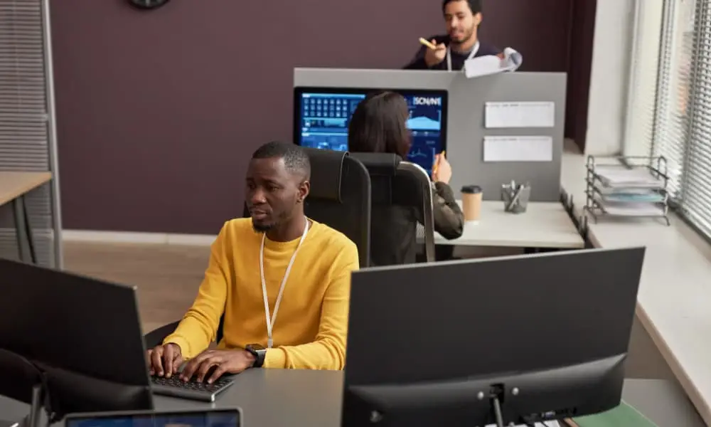 Two software engineers working on proactive I.T. management at their desks for a customer. 