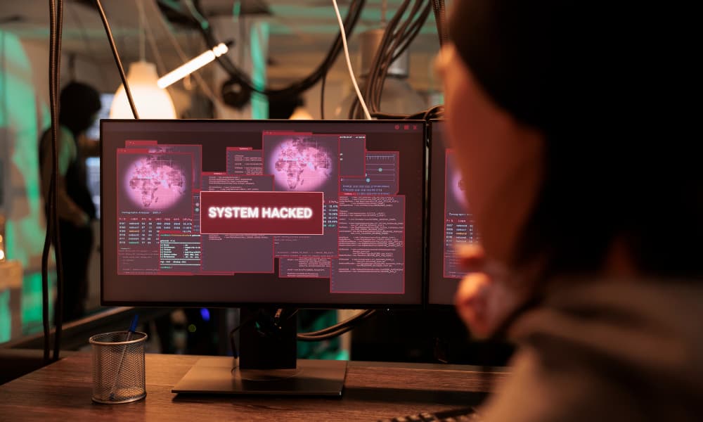 A monitor displaying the message “SYSTEM HACKED.”