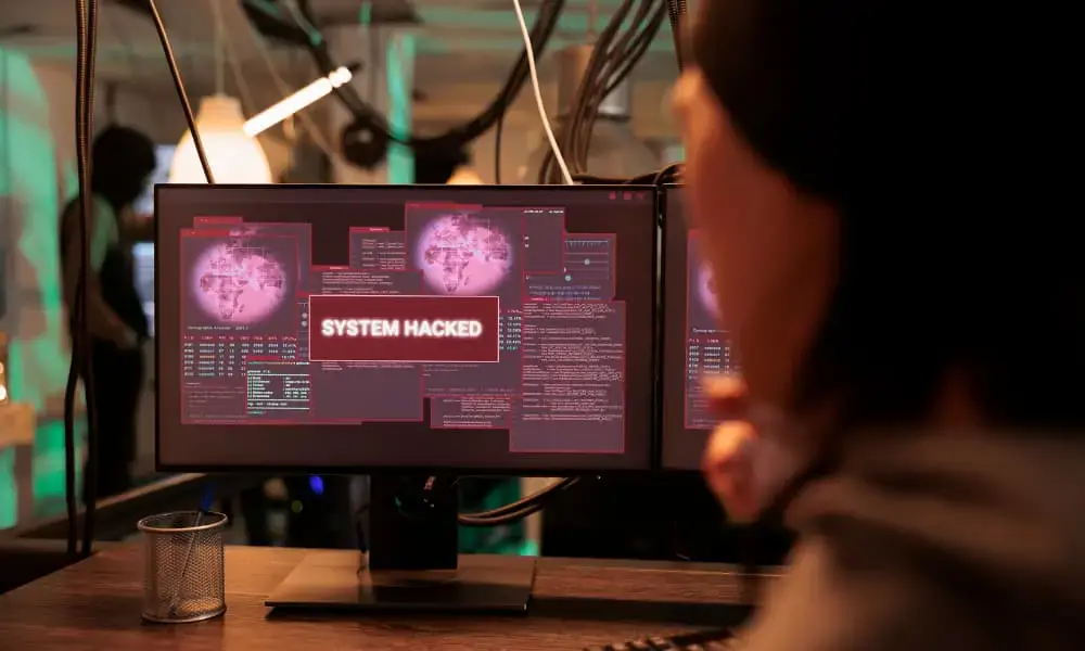 A monitor displaying the message “SYSTEM HACKED.”