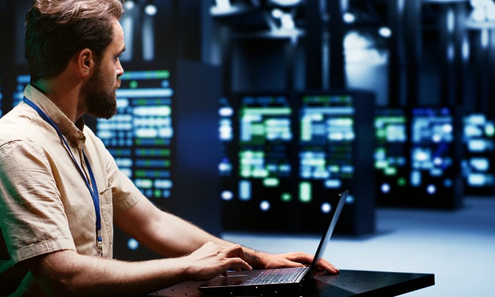 A system administrator typing supercomputer hub disaster recovery plan on laptop.