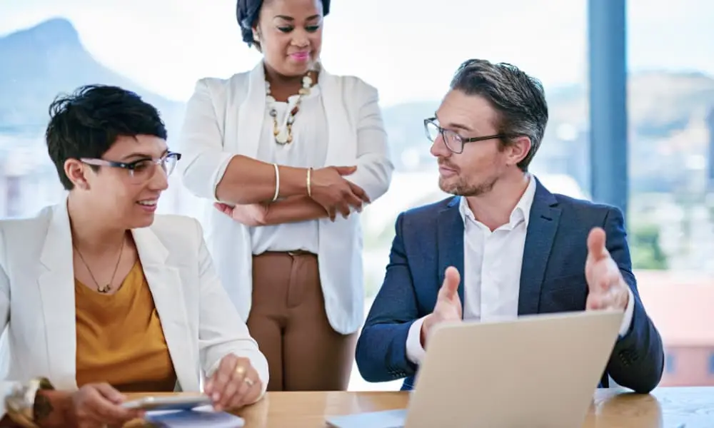 Three business leaders sit at a desk and create their data backup compliance standards.