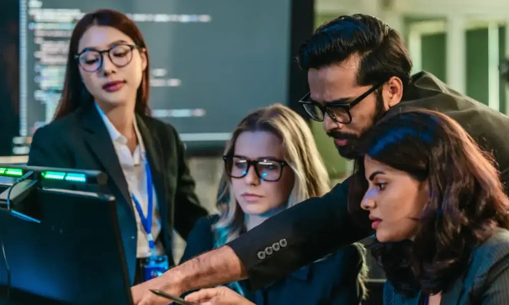 Cybersecurity team collaborating at computers to respond to a cyberattack using an incident response plan.