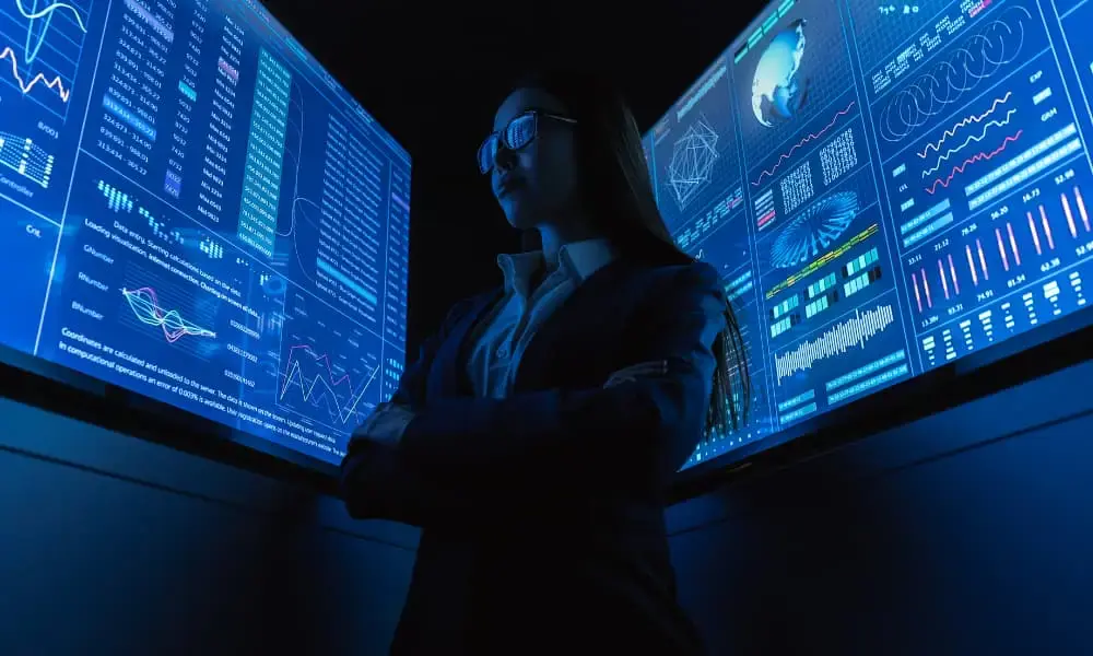 A businesswoman standing near the blue monitor.